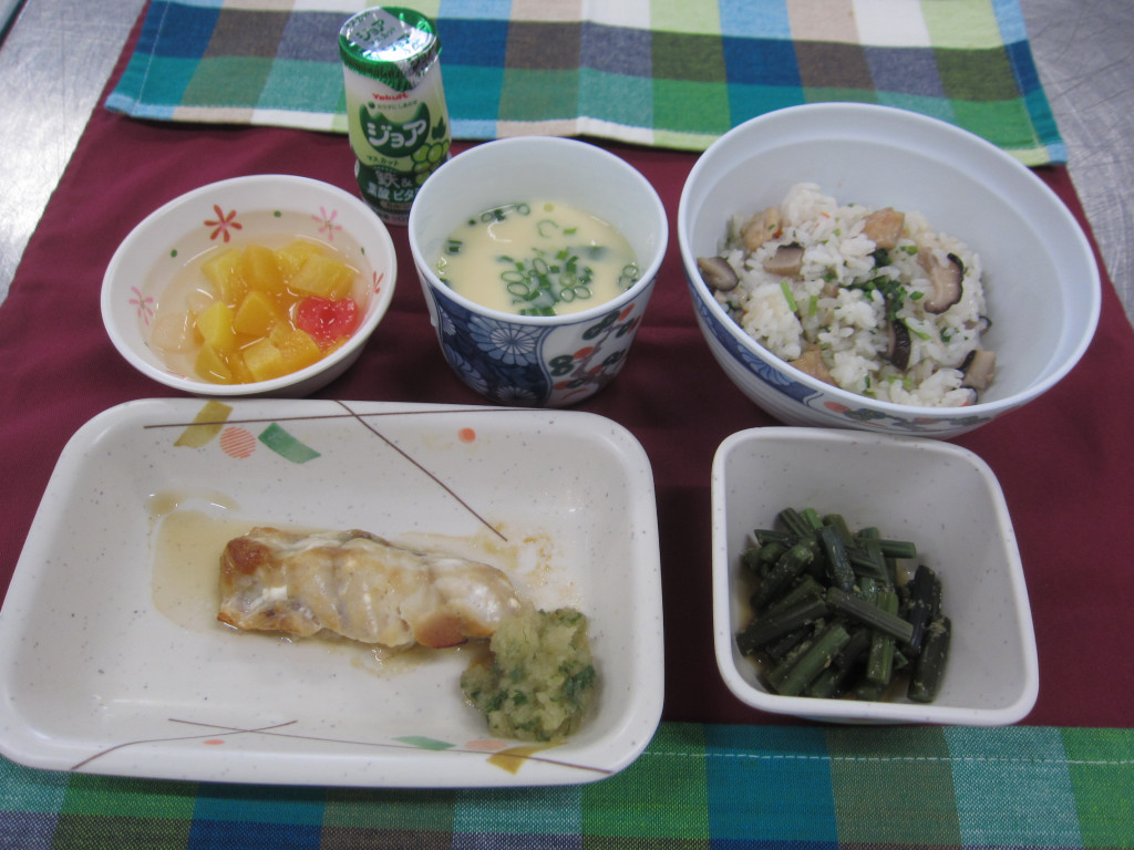 介護施設の食事風景。魚料理、汁物、ご飯、漬物など栄養バランスの取れた献立が提供されている。